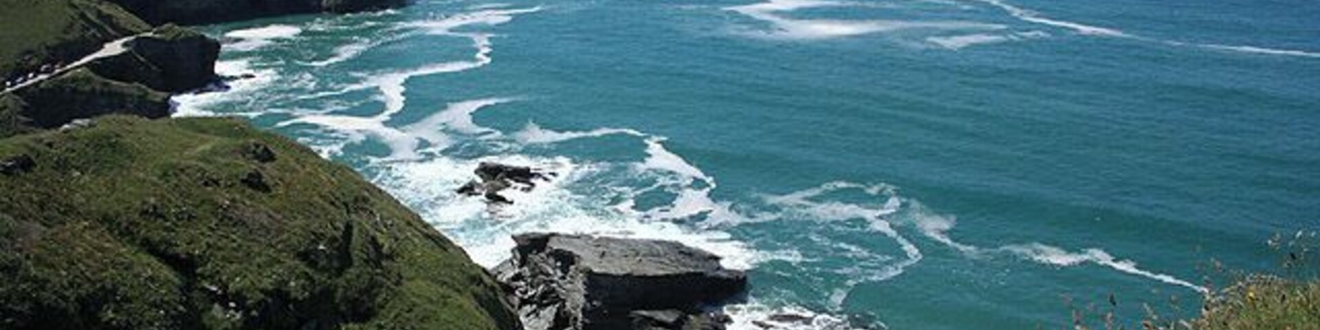 Un paisaje costero con acantilados rocosos, una pequeña isla y el océano.