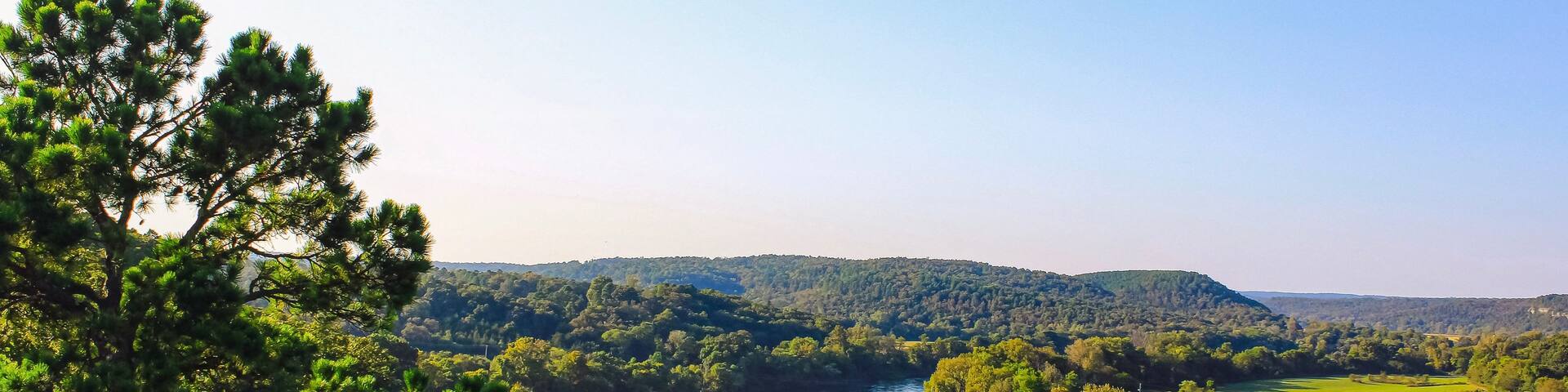 A river winding through a forested valley with hills in the background.