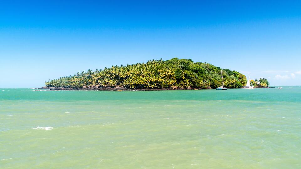 A tropical island with clear turquoise waters and dense green foliage.