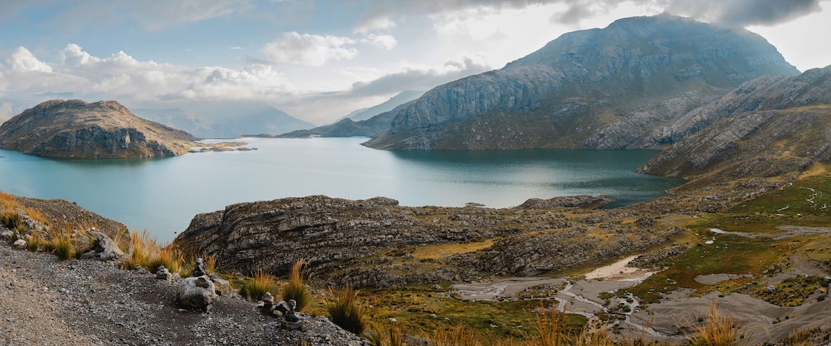 A mountainous landscape with a large lake surrounded by rugged terrain and distant peaks.