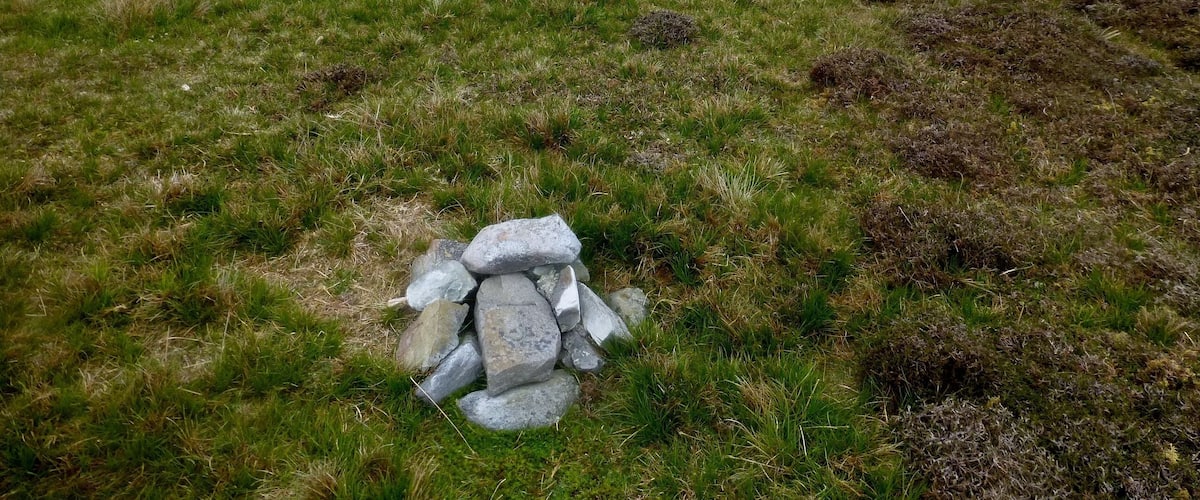 A cairn and a lake with a misty background.