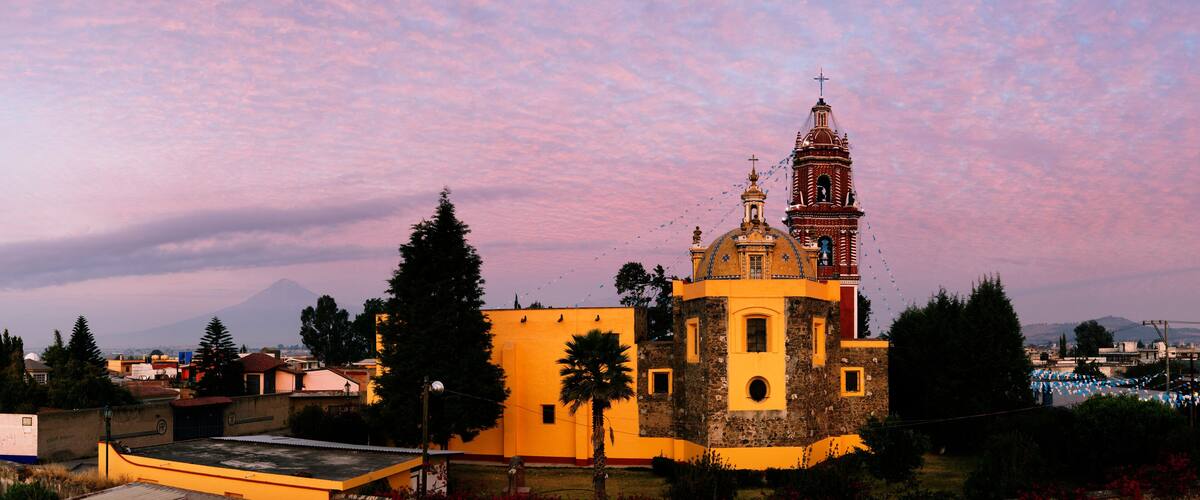 A church with a bell tower, surrounded by trees and buildings.