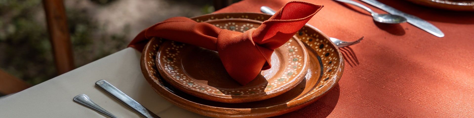 A table set with plates, silverware, and a red napkin.