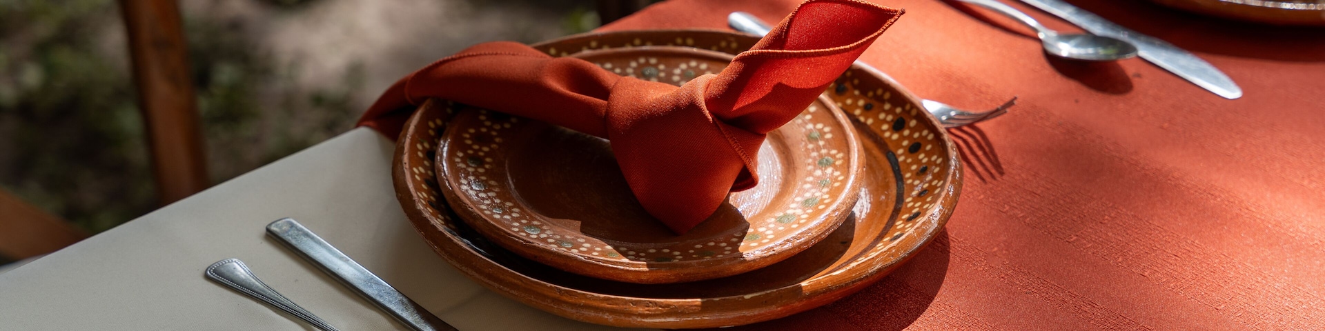 Una mesa dispuesta con platos, cubiertos y una servilleta roja.