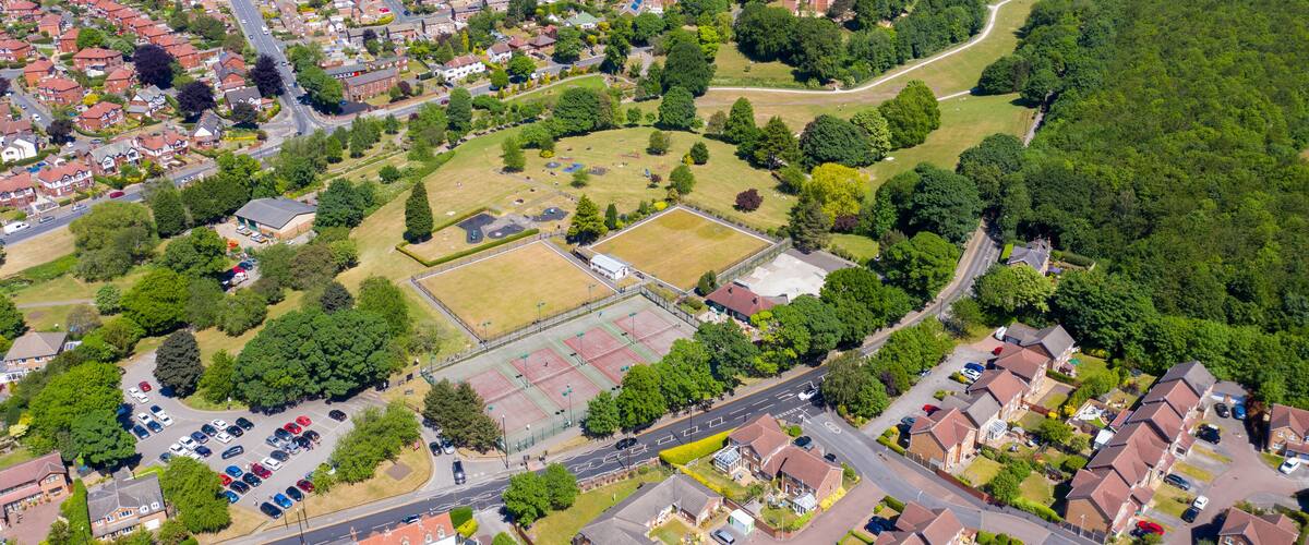 An aerial view of a residential area with houses, roads, and a large green park.