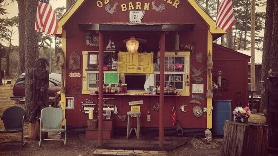 A rustic Ozone Barn Burger stand with a vintage American flag and a state flag.