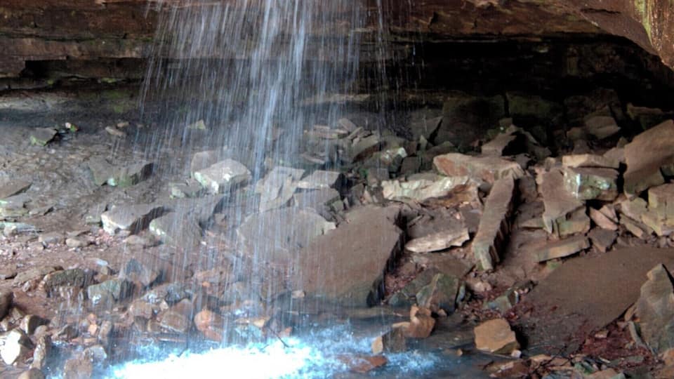 A cave with a waterfall and rocky floor.