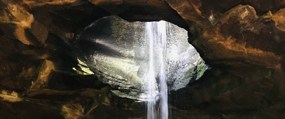 A waterfall in a cave with rocky terrain.