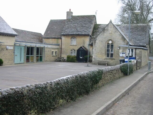 A stone building with a blue door, a small garden, and a paved area in front.