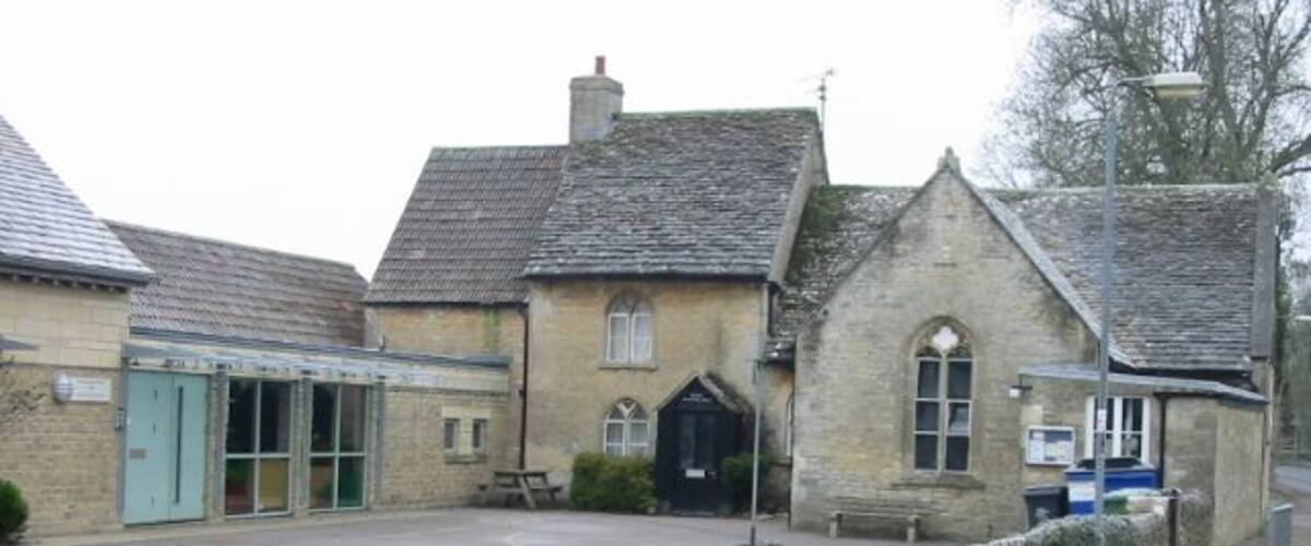 A stone building with a blue door, a small garden, and a paved area in front.