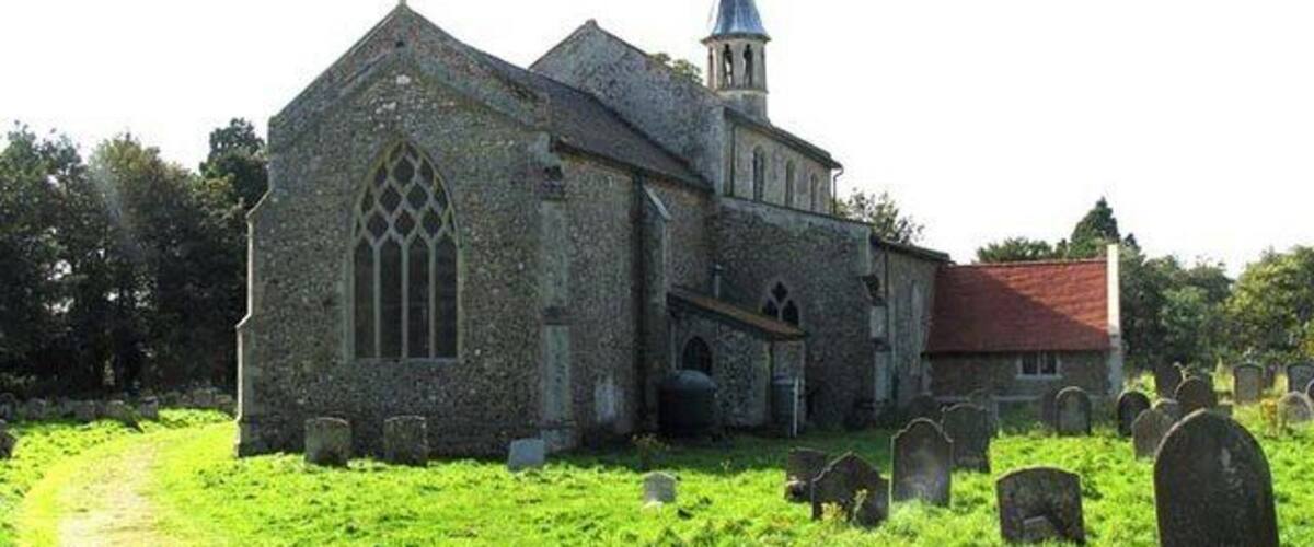 A stone church with a spire and a graveyard.