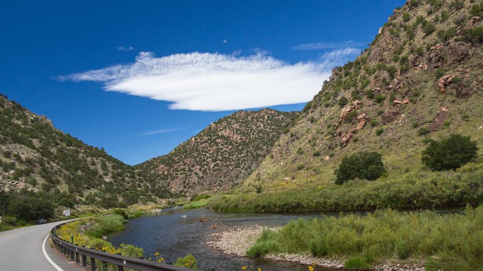 A river winding through a mountainous landscape with a clear blue sky.
