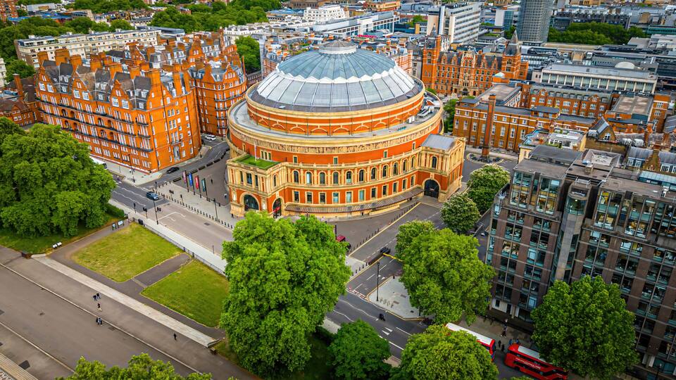 A large circular building with a dome, surrounded by red brick buildings and green trees.