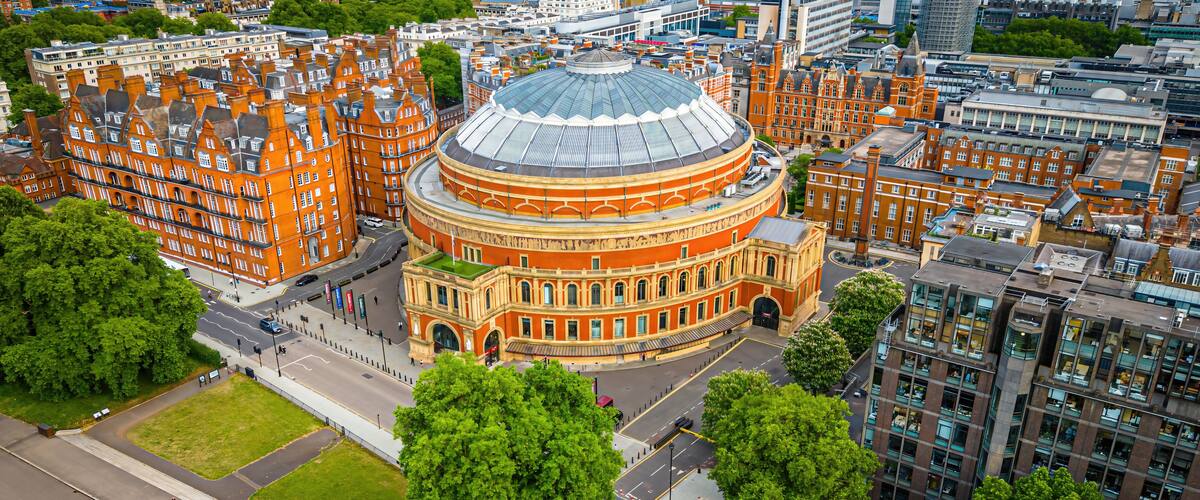 A large circular building with a dome, surrounded by red brick buildings and green trees.