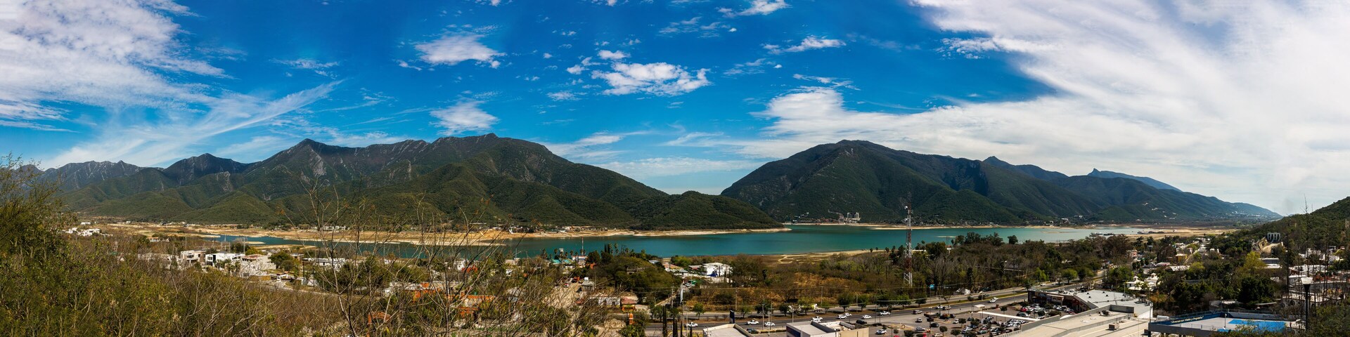 Un pueblo costero con montañas al fondo, una playa y un cielo azul despejado.