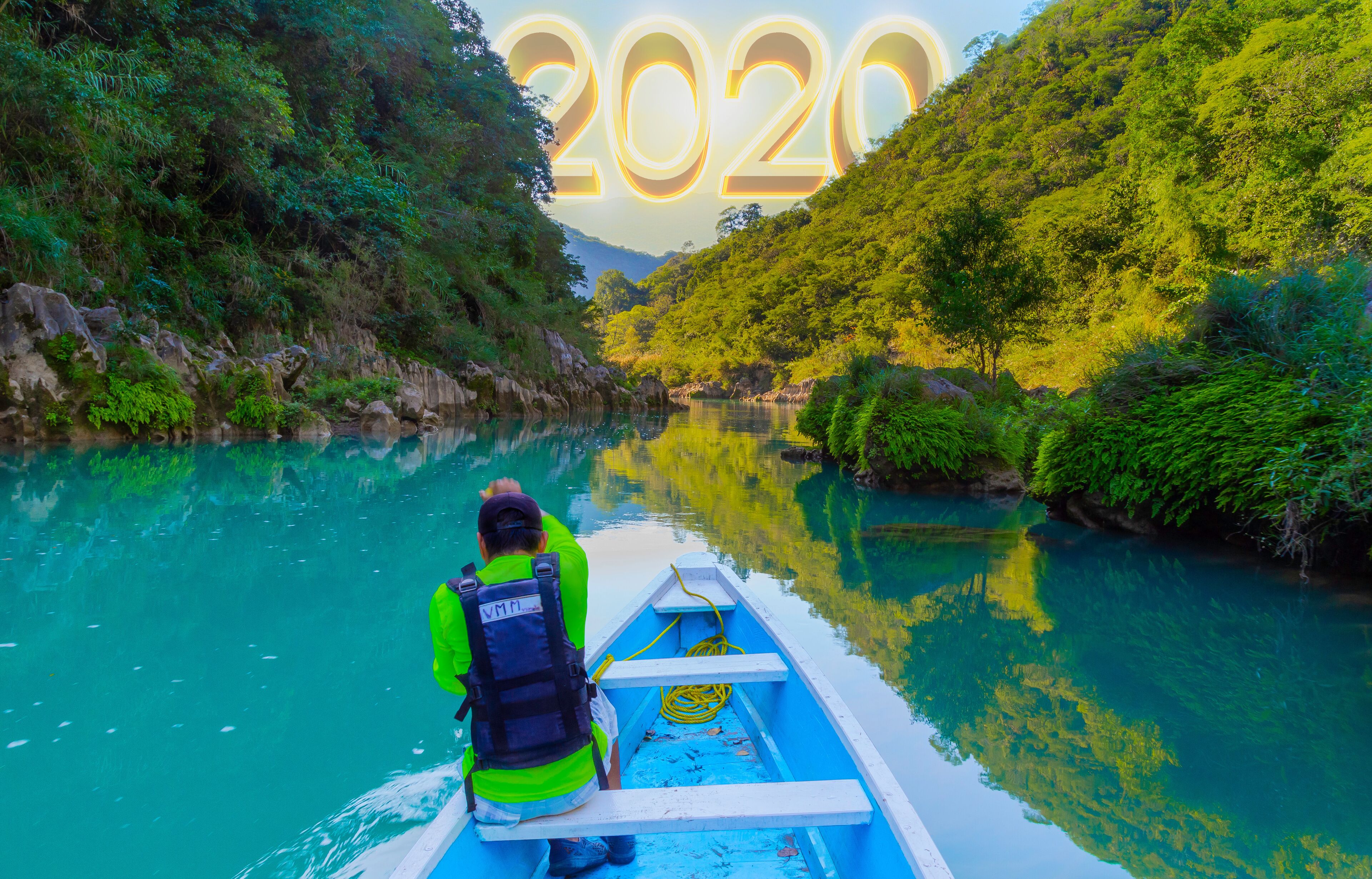 A person in a boat on a river surrounded by lush greenery.