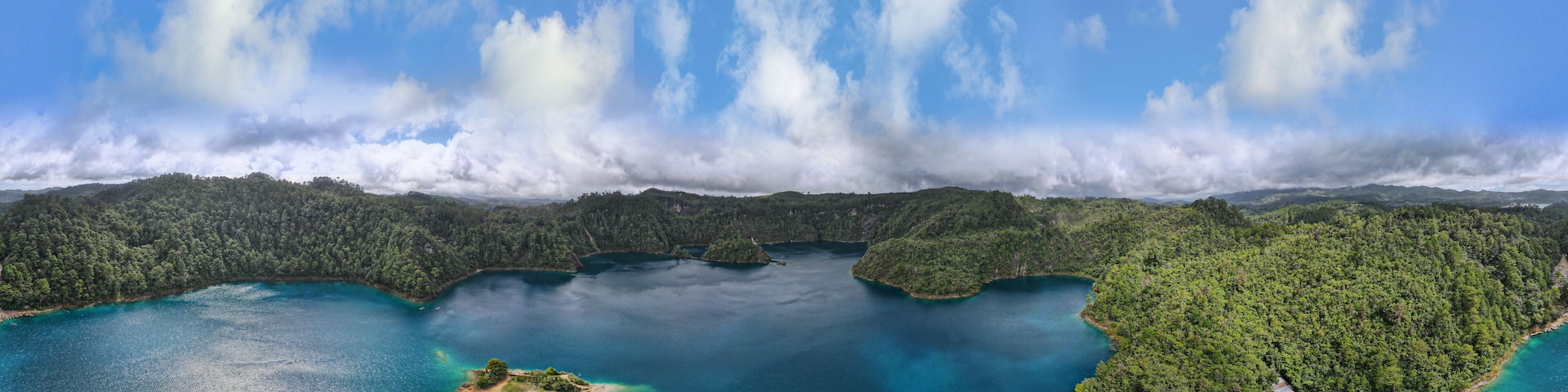 A coastal landscape with a large body of water, several small islands, and a forested area.