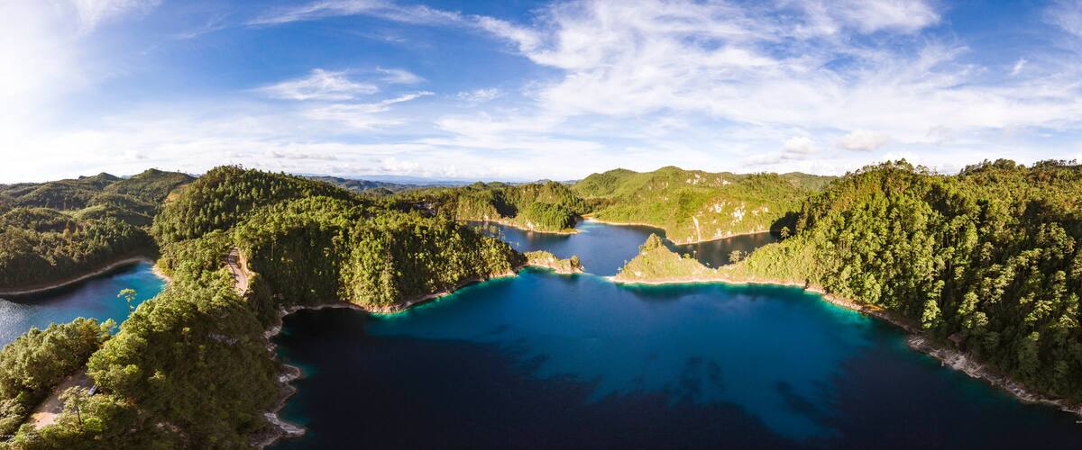 A coastal landscape with a large bay surrounded by dense forests and hills.