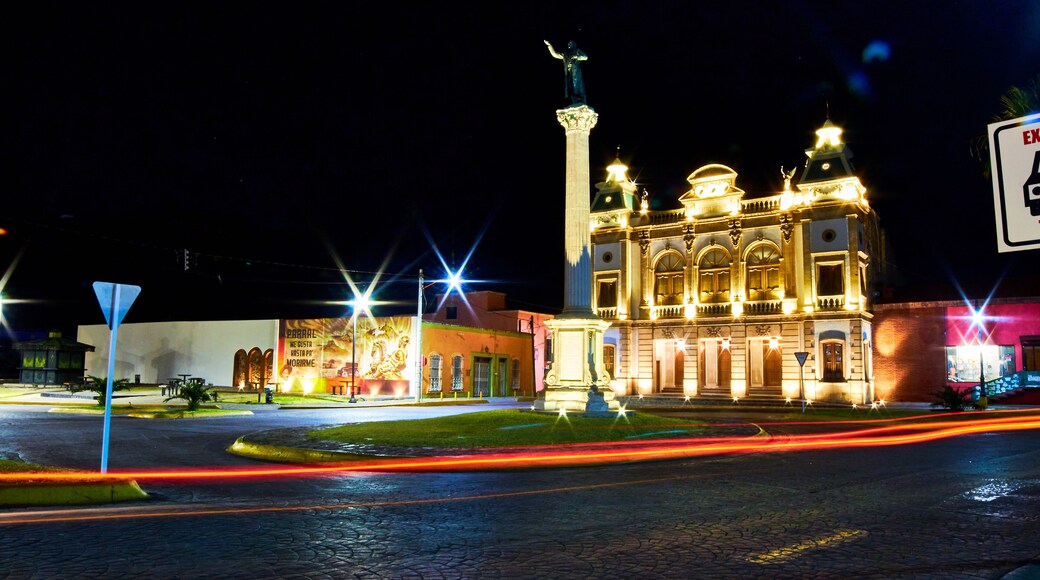 view of street at night with building illuminated, and lights of car in foreground, hidalgo theather in parral chihuahua