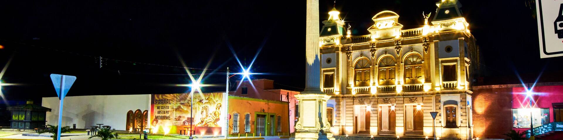 view of street at night with building illuminated, and lights of car in foreground, hidalgo theather in parral chihuahua