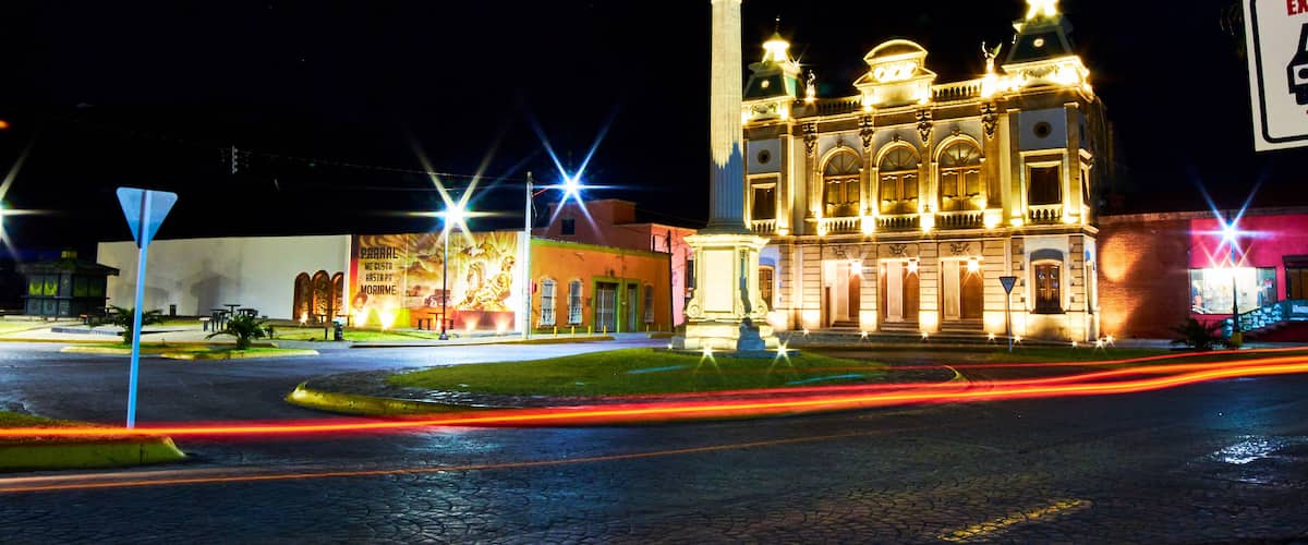 A historic building with ornate architecture and a statue on top, illuminated at night.