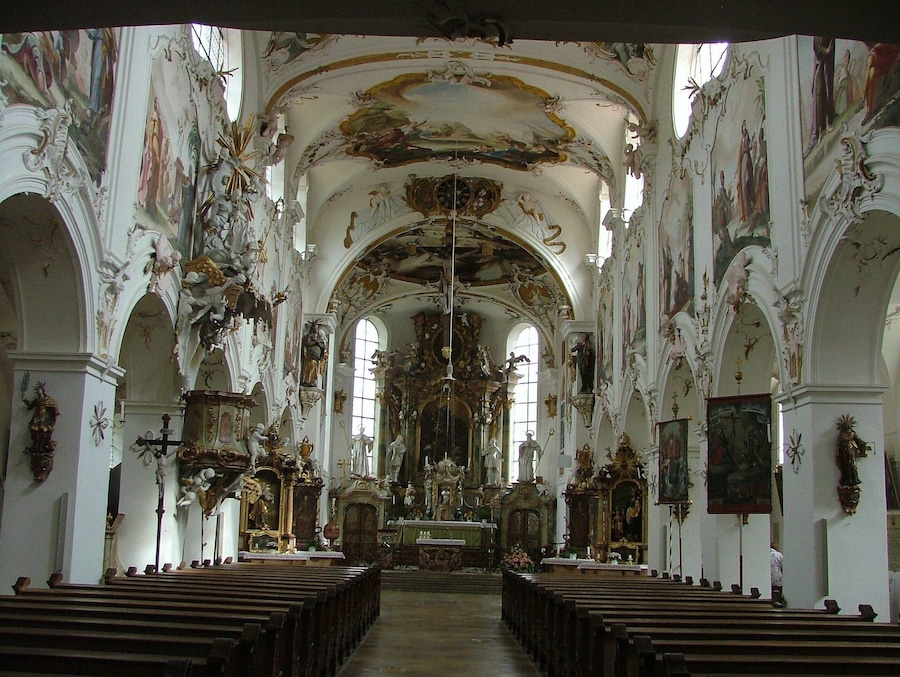 Interior d'una església ornamentada, amb alts sostres, frescos detallats i files de pews.
