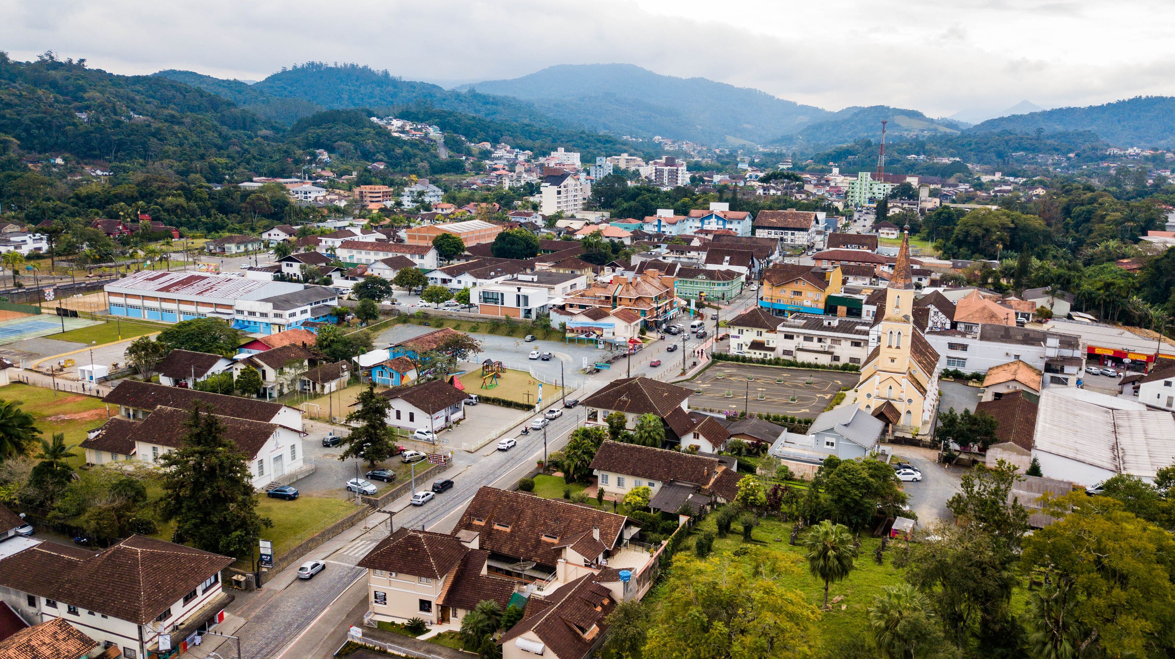 A town with a prominent church steeple, surrounded by residential buildings and a hilly backdrop.