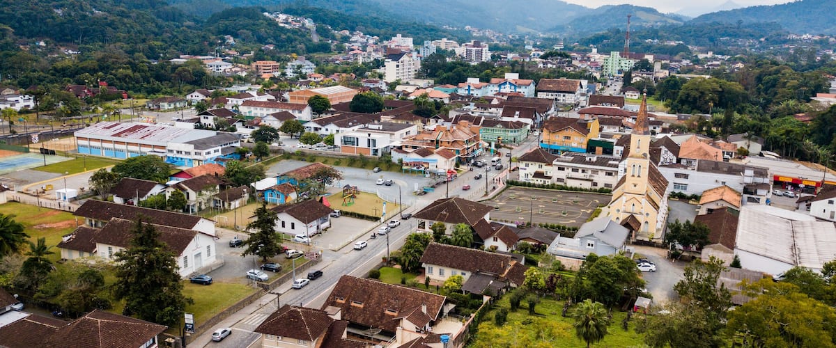 A town with a prominent church steeple, surrounded by residential buildings and a hilly backdrop.