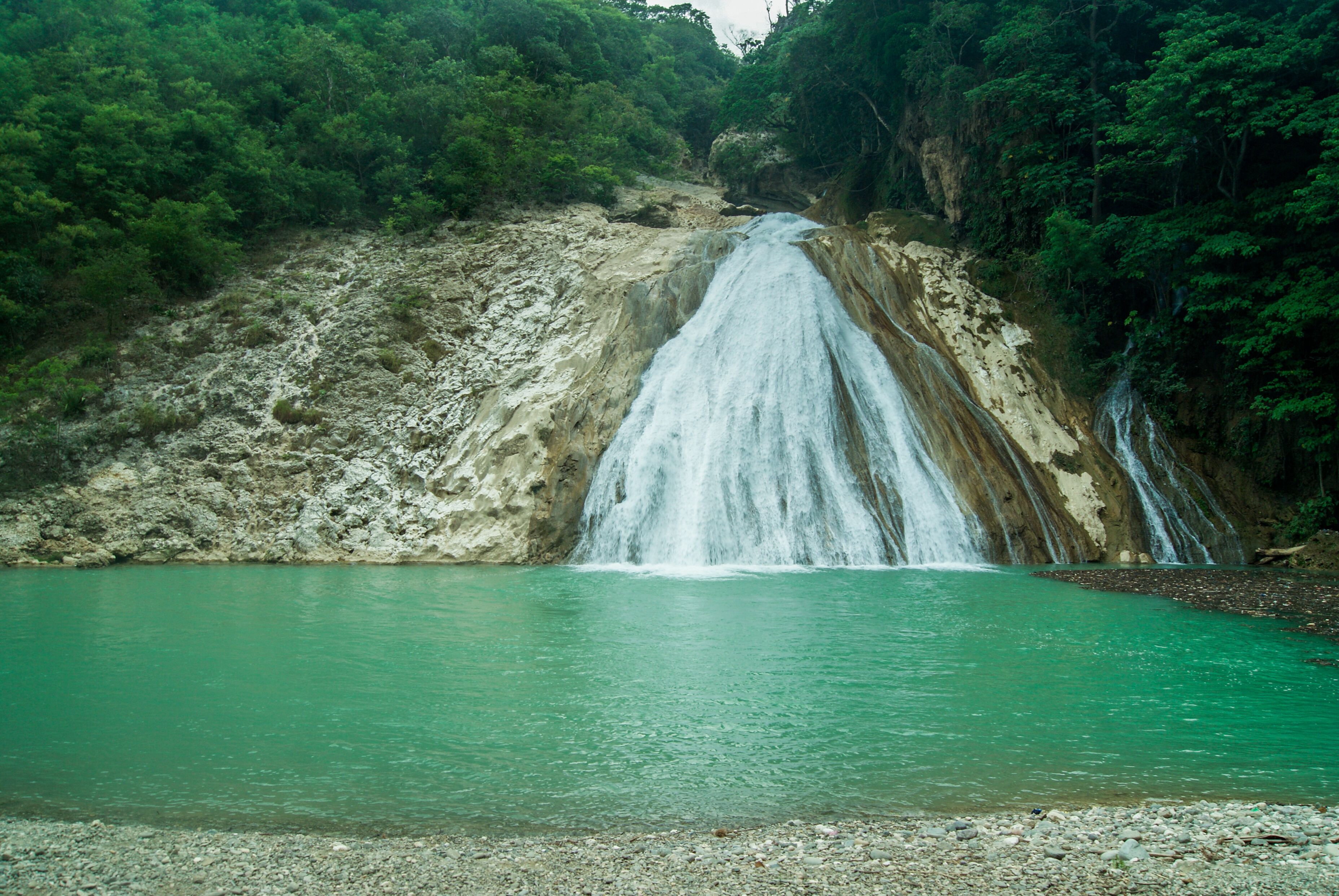 A waterfall cascading into a turquoise pool surrounded by dense forest.