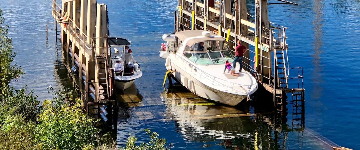 A boat docked at a wooden pier with a rocky shoreline in the background.
