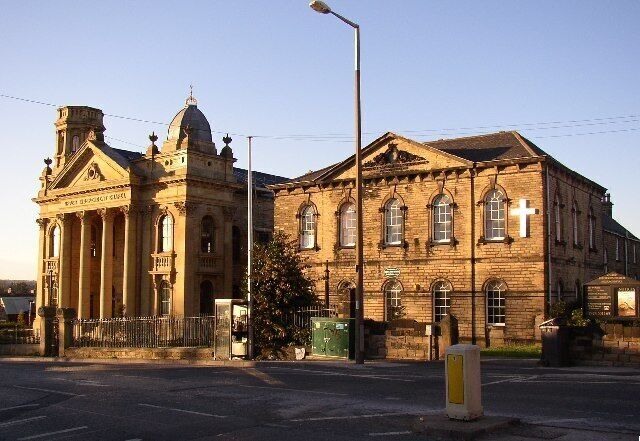 Upper Independent Chapel and Sunday School, High Street, Heckmondwike The building on the right was the Sunday School when it was built in 1856; it has an inscription in the pediment: 'Independent Day and Sabbath Schools. Anno Domini 1856'. It is now the chapel (United Reformed Church) and the newer building next door has been converted into flats. This was built in 1890 and is quite an amazing building, with a Classical front which the CofE of the time would perhaps have considered pagan architecture, and an exuberant tower (Italianate?) on each side.