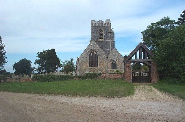 A church with a tall tower and a brick archway.