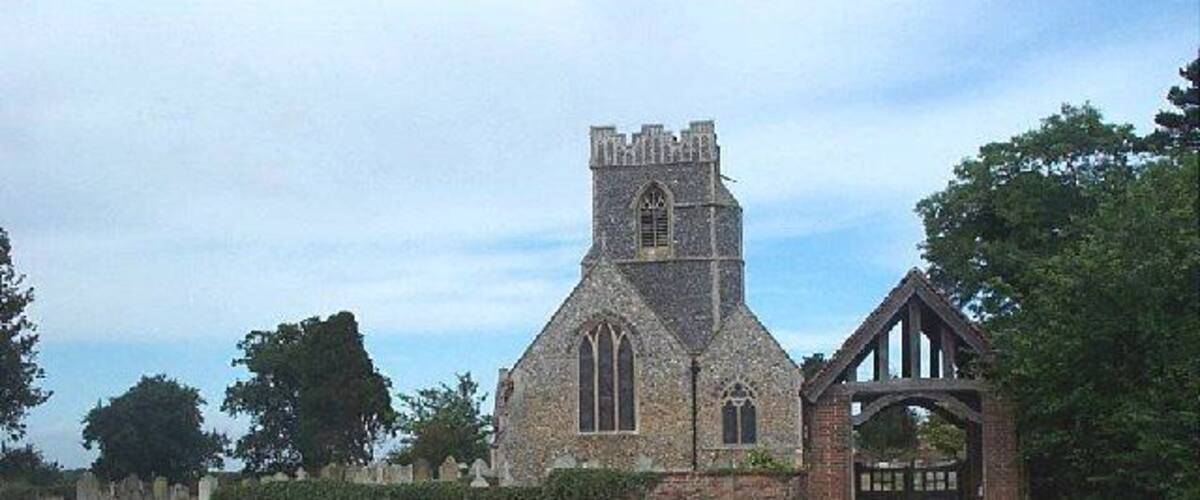 A church with a tall tower and a brick archway.