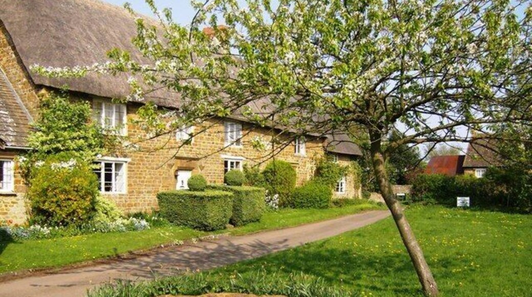 Part of the village green at Epwell, Oxfordshire. On the left is Village House, with Charlie's Cottage beyond. Both are thatched 17th-century stone cottages. The stone area with grey slates in the foreground is a sundial. See 449049