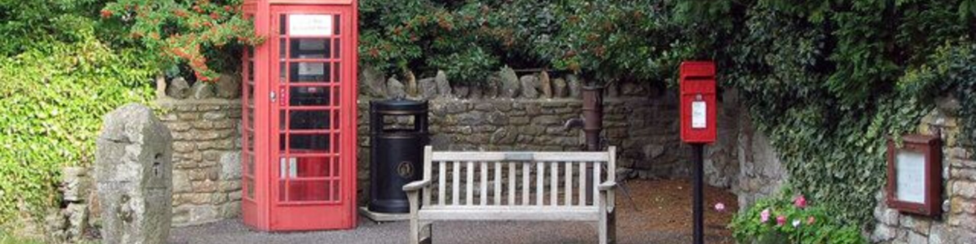 Convenient corner Tucked in a corner of the small village of Burrington, opposite the church. Here you can have a sit down, make a call, dispose of your rubbish, post a letter, pump some water, smell the flowers, appreciate modern art and organise your weekend via the notice board.