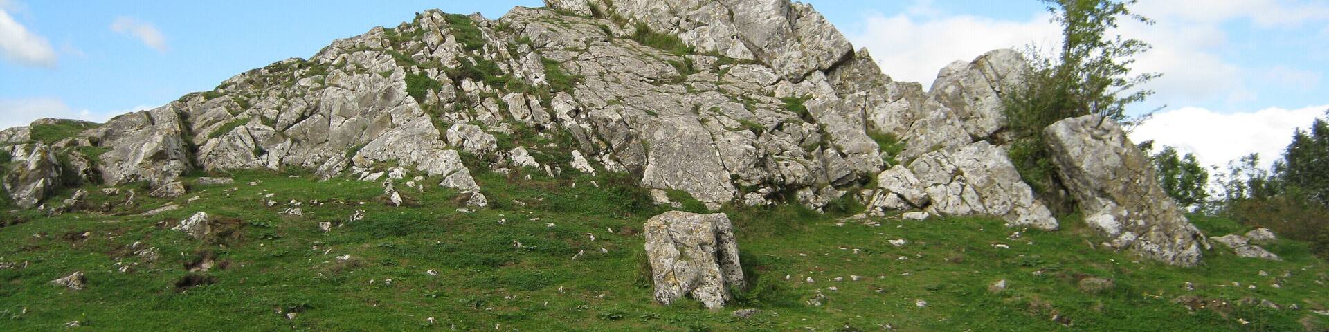 A rocky hill with sparse grass and a clear blue sky.
