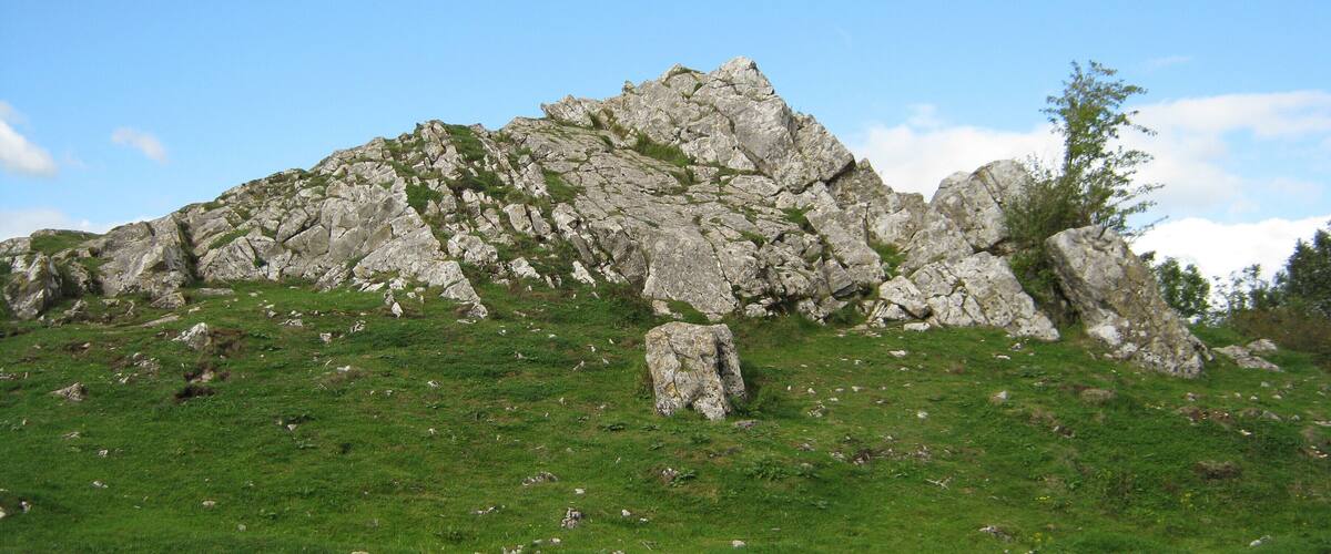 A rocky hill with sparse grass and a clear blue sky.