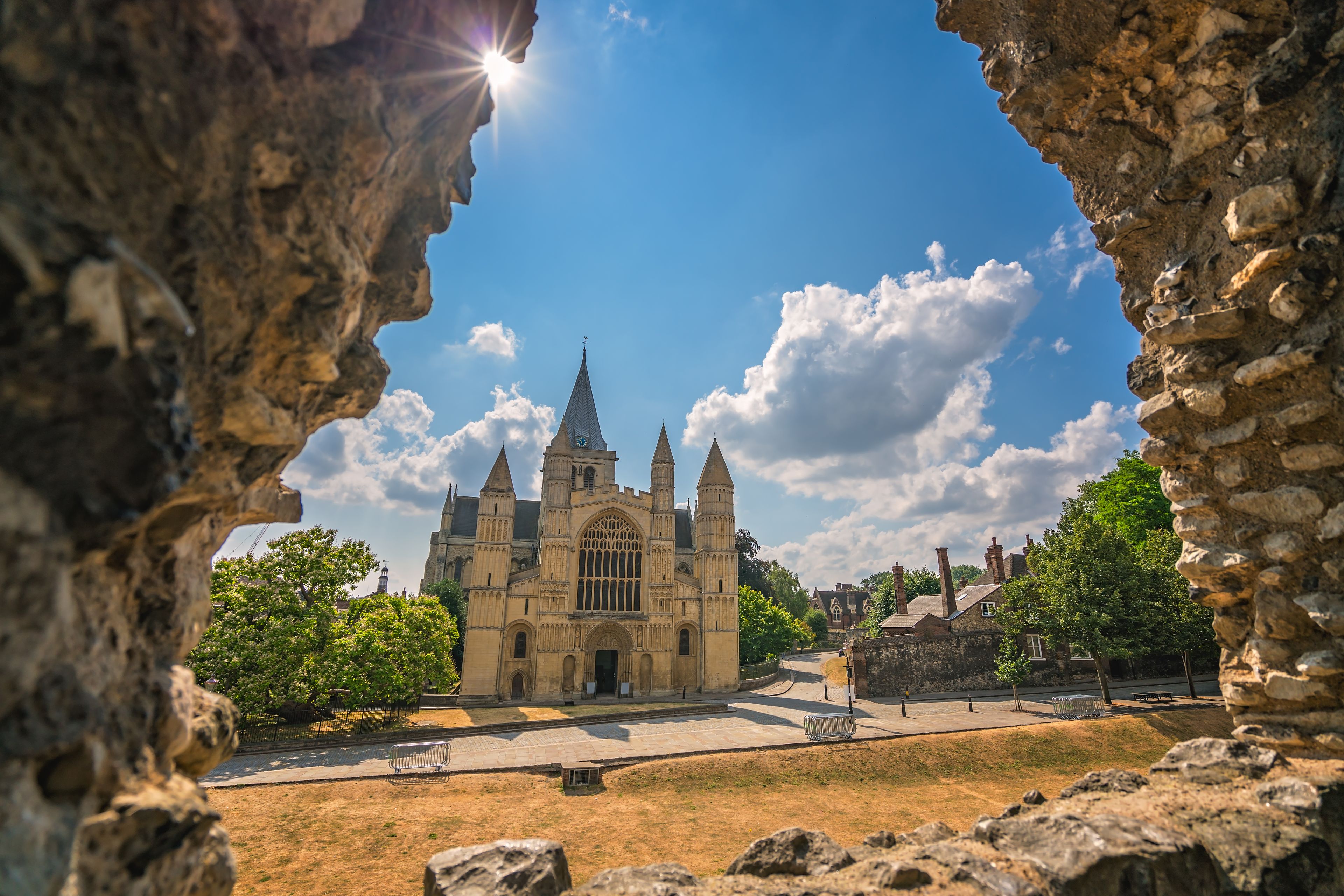 Una catedral con un rosetón grande, rodeada de ruinas de piedra y follaje.