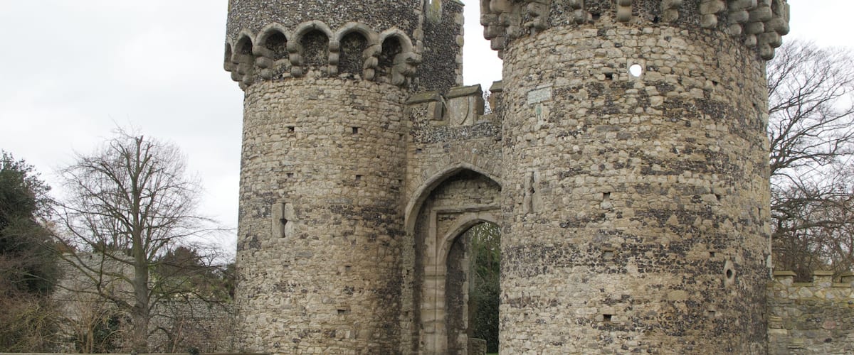 A medieval stone castle with two prominent towers and a large arched entrance.
