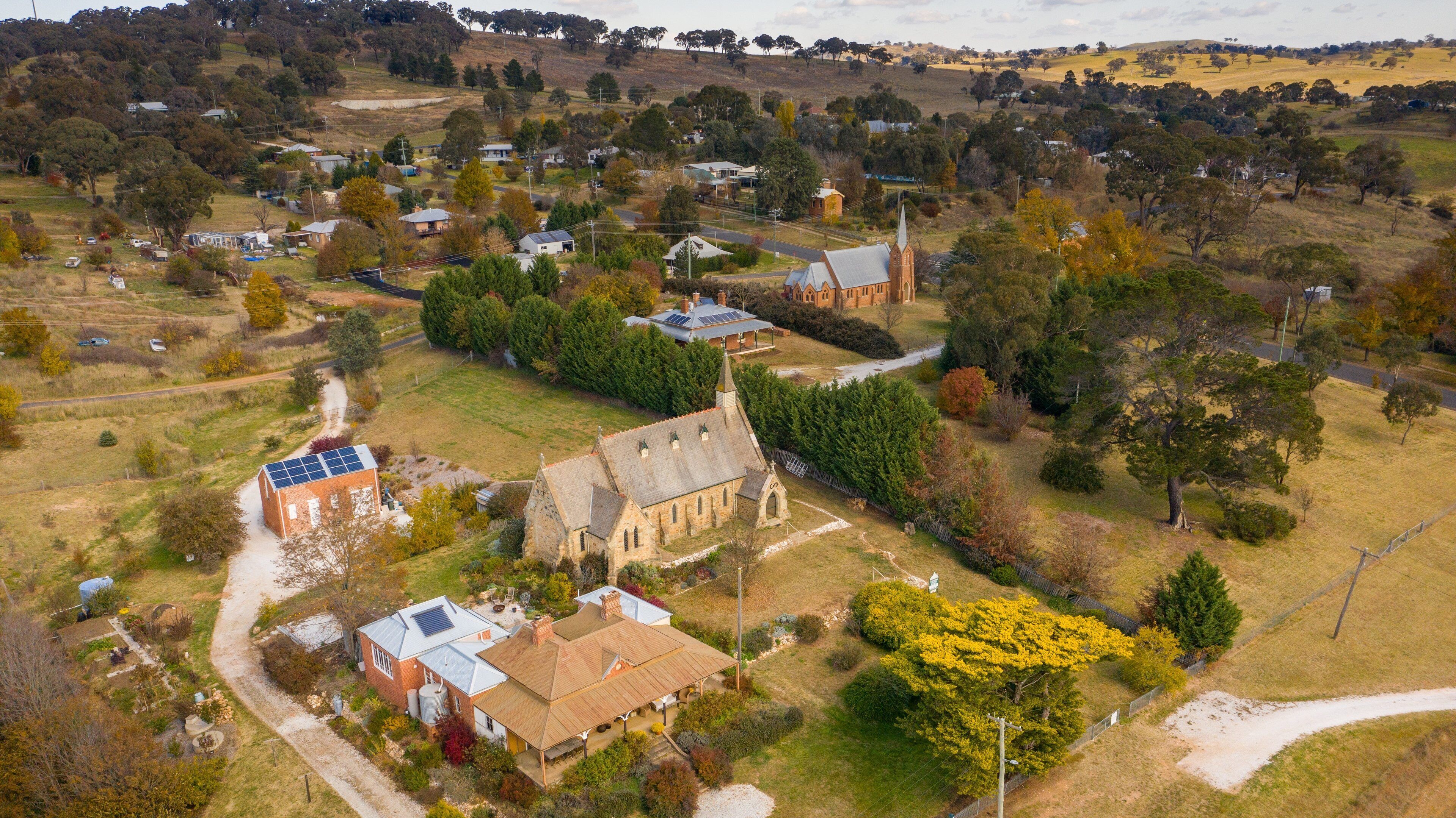 An aerial view of a rural village with houses, a church, and surrounding greenery.
