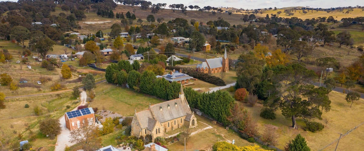 An aerial view of a rural village with houses, a church, and surrounding greenery.