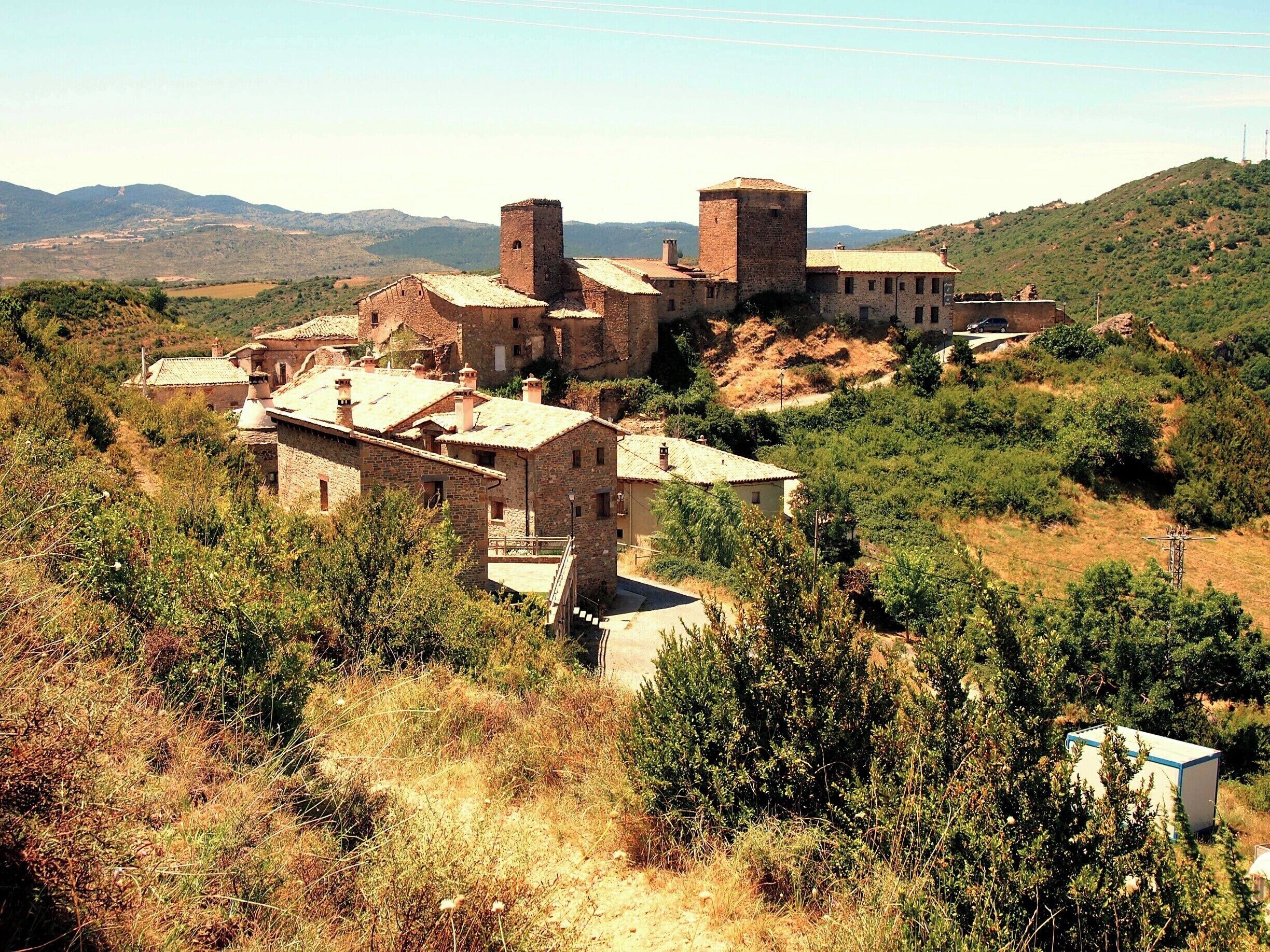 Un pueblo histórico con edificios de piedra y una torre destacada.