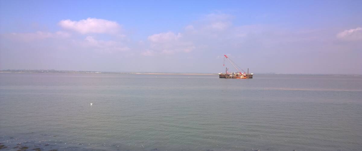 A calm sea with a distant offshore platform.