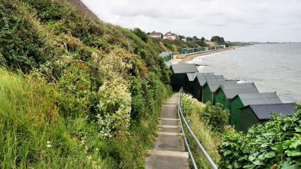 A coastal path with steps leading to beach huts, overlooking the sea.