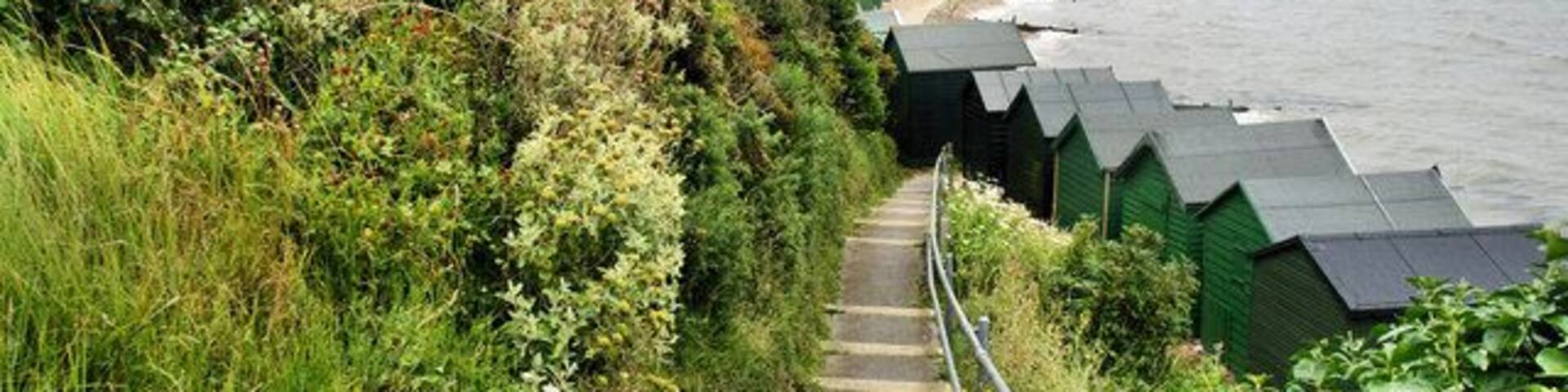 A coastal path with steps leading to beach huts, overlooking the sea.