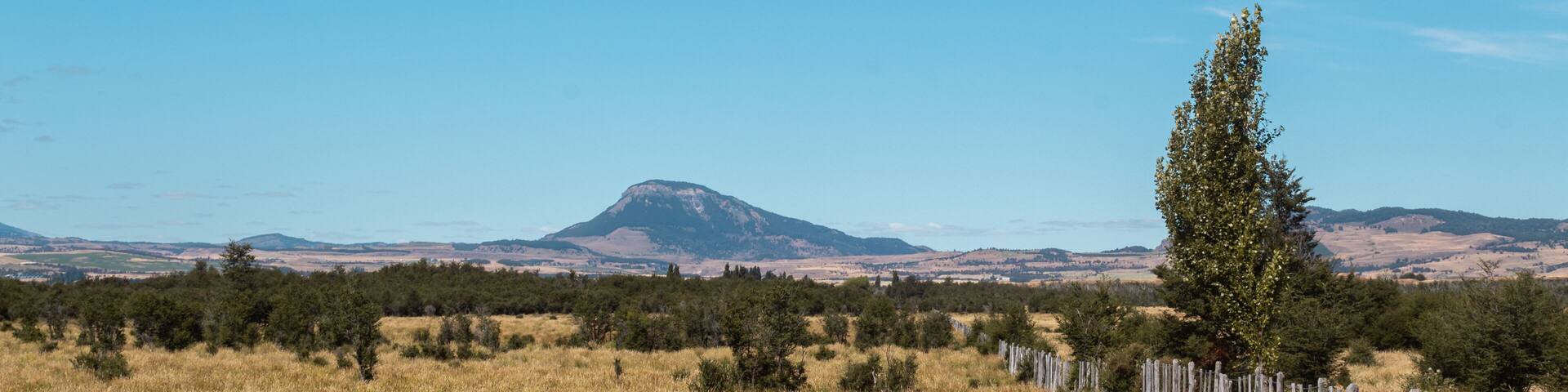 Día soleado en el campo con montes de fondo.