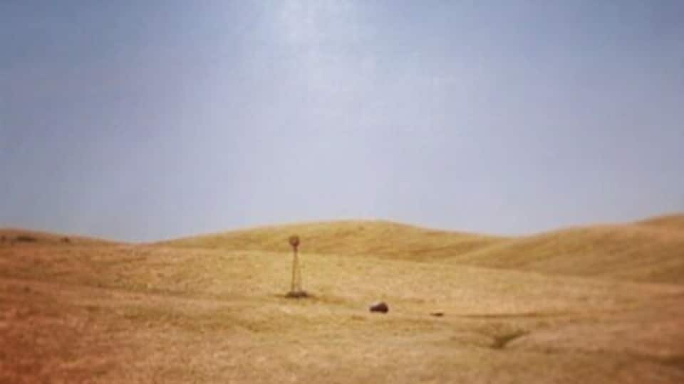 A grassy field with a small pole in the center.