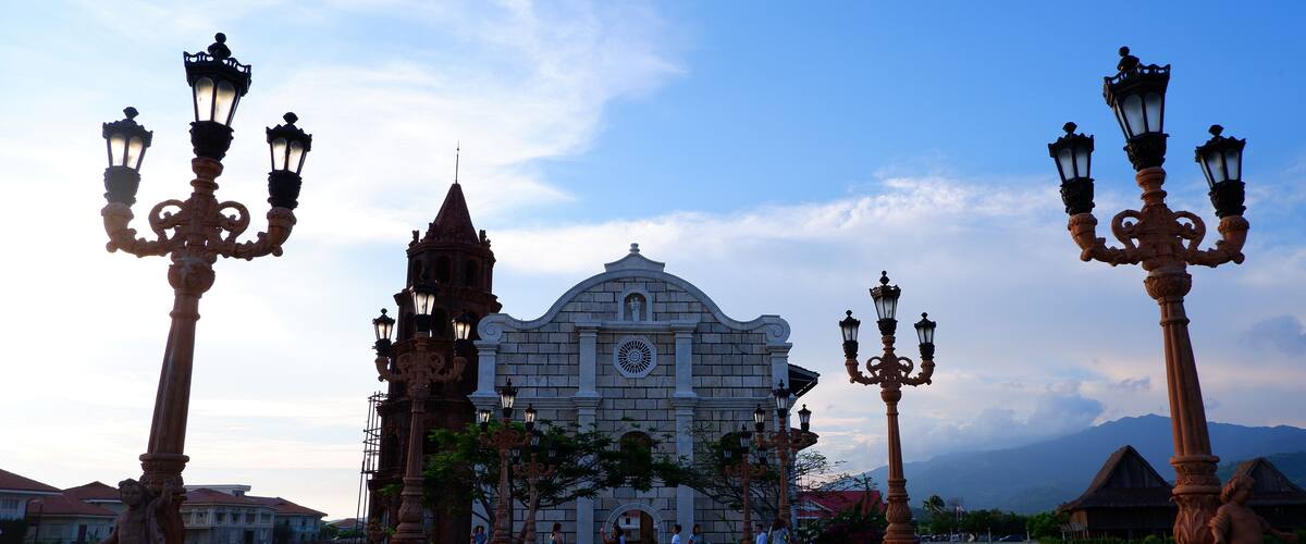 A historic building with ornate street lamps and a river in the foreground.