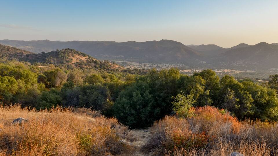 A mountainous landscape with dense forests and a clear sky.