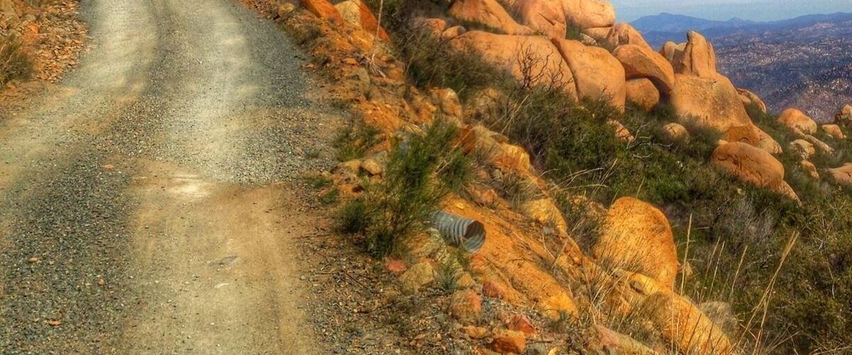 A gravel road winding through a rocky landscape with large boulders and sparse vegetation.
